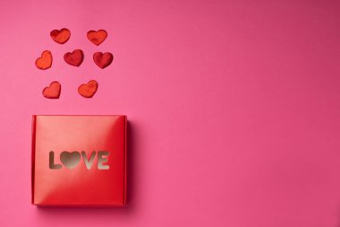 Kırmızı kutu kelime ile aşk kalp şeklinde ve kırmızı kalpler gül arka planda