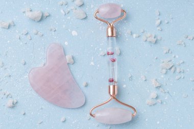 Mavi arka planda gua sha masaj aleti ve deniz tuzu. Güzellik yüz aletleri kavramı. Üst görünüm