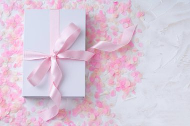Hediye edilen beyaz bir arka plan pembe konfetiyle pembe kurdeleli beyaz bir kutu. Sevgililer Günü, Mutlu Kadınlar Günü, Anneler Günü, Doğum günü