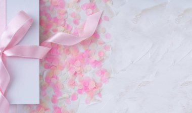 Hediye edilen beyaz bir arka plan pembe konfetiyle pembe kurdeleli beyaz bir kutu. Sevgililer Günü, Mutlu Kadınlar Günü, Anneler Günü, Doğum günü