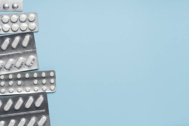 Mavi arka planda beyaz haplar, üst manzara. Farklı ilaçlar, haplar, ilaç kapsülleri. Tıp konsepti, geçmiş. Metin yeri