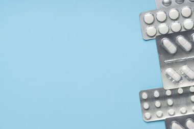 Mavi arka planda beyaz haplar, üst manzara. Farklı ilaçlar, haplar, ilaç kapsülleri. Tıp konsepti, geçmiş. Metin yeri.