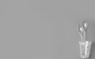 Gri arka planda tek kullanımlık bardaklar ve kaşıklar. İçki rejimi. Mesaj için yer..