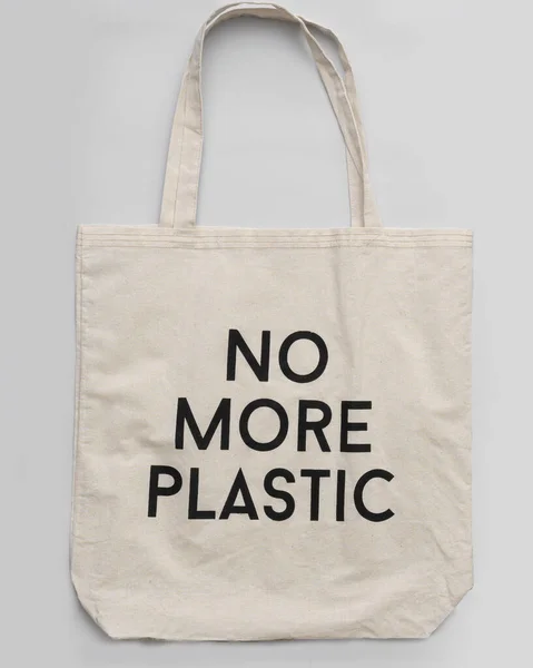 Tekrar kullanılabilir alışveriş torbası artık gri arka planda plastik olmayacak. Gri arkaplanda pamuk alıcısı, metin için yer.