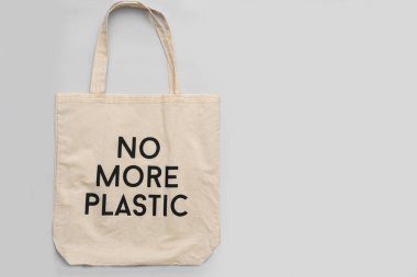 Tekrar kullanılabilir alışveriş torbası artık gri arka planda plastik olmayacak. Gri arkaplanda pamuk alıcısı, metin için yer.