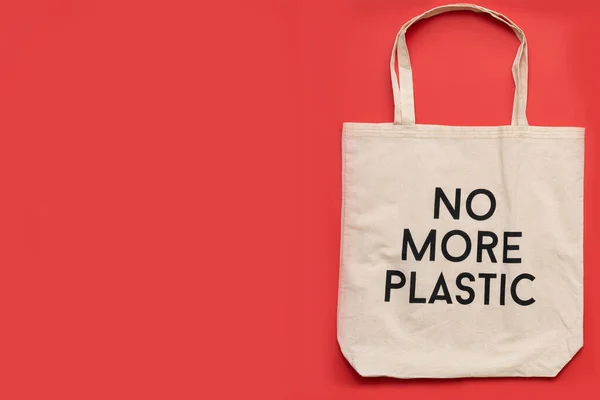 Tekrar kullanılabilir alışveriş torbası kırmızı arka planda plastik olmayacak. Gri arkaplanda pamuk alıcısı, metin için yer.