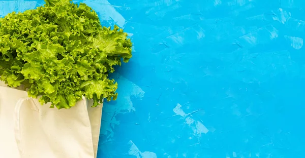 Taze salata yaprakları mavi çimento arka planda beyaz eko torba içinde sıfır atık kavramı. Salat sulu olgun eko biyolojik taze arka plan görüntüsü. Metin için yeri olan banner