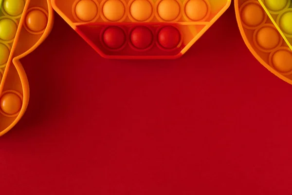 Color pop it juguetes antiestrés para niños. octágono rojo y naranja, corazón y círculo sobre fondo rojo. Pop it toy.Copy space.Place para el texto — Foto de Stock
