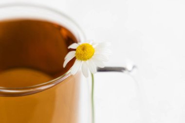 Papatya çayı ve papatya çayı beyaz çimento masasında cam bardakta. Bitki çayı. Yan görünüm.