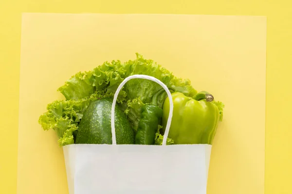 Sağlıklı beslenme geçmişi. Sarı arka planda sebze paketinde vejetaryen yiyecekler. Market alışverişi ve temiz yeme konsepti..