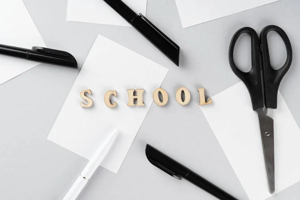 Terug naar school. Word School op houten blokken student bestudeert accessoires op grijze achtergrond. School achtergrond. Onderwijs achtergrond. — Stockfoto