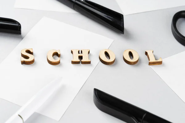 Terug naar school. Word School op houten blokken student bestudeert accessoires op grijze achtergrond. School achtergrond. Onderwijs achtergrond. — Stockfoto