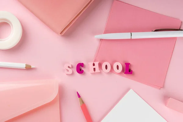 Roze schoolspullen en woordschool op roze achtergrond. Terug naar school concept. Bovenaanzicht — Stockfoto