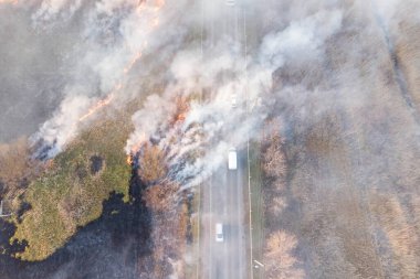 Yol kenarındaki yanan odunlar ve hareket halindeki araçlar, insansız hava aracı fotoğrafçılığı.