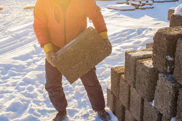 a man working as a loader, loads blocks from an arbolite, in the backlight of the sun