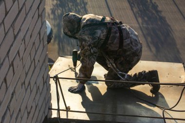 Güvenlik halatına sigortalı bir endüstriyel dağcı yüksek irtifada metal yapılar kurma görevini yerine getiriyor.