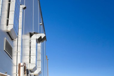 Endüstriyel bilgi dışında büyük havalandırma kanalları ve mavi gökyüzüne karşı termal yalıtım.