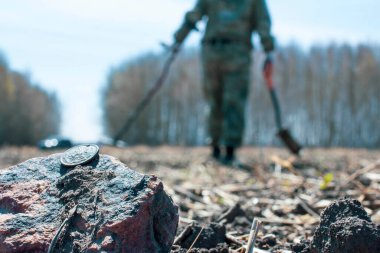 Eski bir savunma kalesinin uçsuz bucaksız genişliklerinde metal dedektörü olan bir adam antik sikkeleri ve tarihi eserleri ararken ön plan ve arka plan bokeh etkisi ile bulanıklaşır.