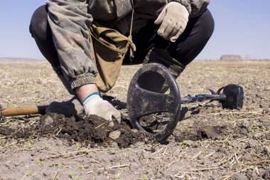 Eski bir savunma kalesinin uçsuz bucaksız genişliklerinde metal dedektörü olan bir adam antik sikkeleri ve tarihi eserleri ararken ön plan ve arka plan bokeh etkisi ile bulanıklaşır.