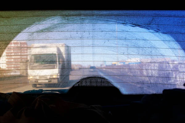 dirty rear window of a car, view from the passenger compartment to the roadway, front and background blurred with bokeh effect