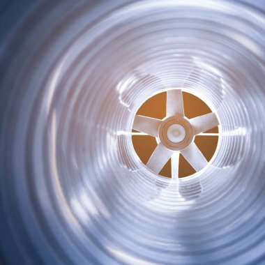 Arka plandaki fonda bulunan egzoz pervanesinin içerisindeki galvanize çelik hava kanalının yakın çekim görüntüsü, ön ve arka plan bokeh etkisi ile bulanıklaşır.