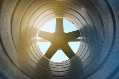 Arka plandaki egzoz vantilatöründeki galvanize çelik hava kanalının içerisinden yakın çekim görüntüsü Bokeh etkisi ile ön ve arka plan bulanıklaşır.