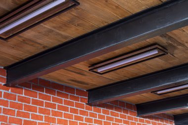 Demir kirişler arasındaki ahşap tavanda parlak lamba sergileniyor, apartman yenilenmesinin tasarım çözümünde, ön ve arka planlar bokeh etkisi ile bulanıklaşıyor