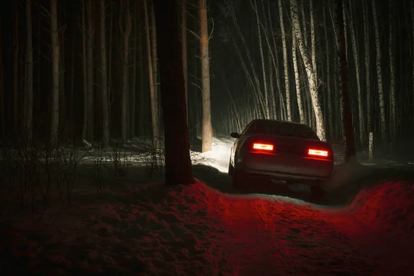 sports car with high beam on in a winter pine forest at night, front and background blurred with bokeh effect