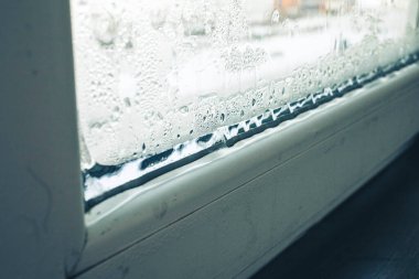 Bir dairede plastik bir pencerenin donması, cam, yamaç ve pencere pervazının donması, ön ve arka plan bokeh etkisi ile bulanıklaşır.