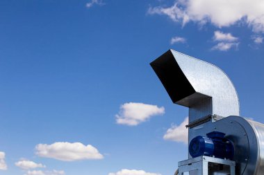 Güzel mavi gökyüzünün arka planına karşı havalandırma sisteminde asonkronize motor, ön plan ve arka plan bokeh etkisi ile bulanıklaşır.