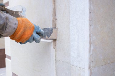 Binayı bitiren granit mermeri elle yerleştiren bir adam, bir el aleti ile yakın plan bir müzenin yeniden inşasını yapan, çatlaklı doğal taş ve özel bir bileşikle restorasyon yapan bir adam.