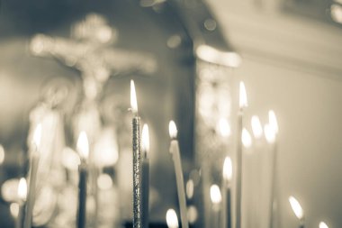 Tapınaktaki mumlar haçın yanında, ön ve arka planlar bokeh etkisi ile bulanıklaşıyor.