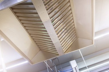 Paslanmaz çelik egzoz kaputu, yarı bitmiş ürünlerin üretiminde büyük bir endüstriyel mutfağa yakın plan.