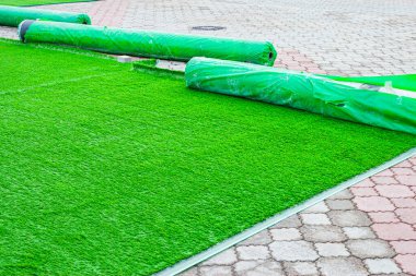 Eski asfalt döşemeler üzerine yapay yeşil çimen döşemek ve yerleştirmek peyzaj için geçici bir çözümdür..