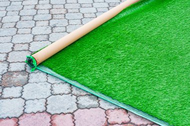 Eski asfalt döşemeler üzerine yapay yeşil çimen döşemek ve yerleştirmek peyzaj için geçici bir çözümdür..