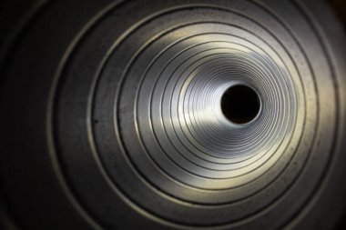 Arka plandaki egzoz vantilatöründeki galvanize çelik hava kanalının içerisinden yakın çekim görüntüsü Bokeh etkisi ile ön ve arka plan bulanıklaşır.