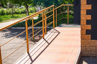 Özürlü insanların amaçlanan işlevini yerine getiremeyen bir binaya girmesi için zayıf bir rampa; inşaattaki yolsuzluk ve uygun olmayan onarım çalışmaları