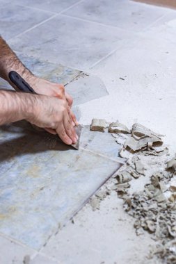 Bir inşaat işçisi odayı tamamlamak için yere dökülen tutkalı kazıyarak temizler..