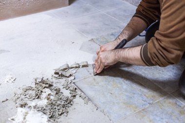 Bir inşaat işçisi odayı tamamlamak için yere dökülen tutkalı kazıyarak temizler..