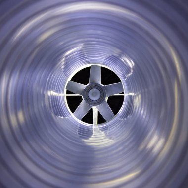 Arka plandaki egzoz vantilatöründeki galvanize çelik hava kanalının içerisinden yakın çekim görüntüsü Bokeh etkisi ile ön ve arka plan bulanıklaşır.