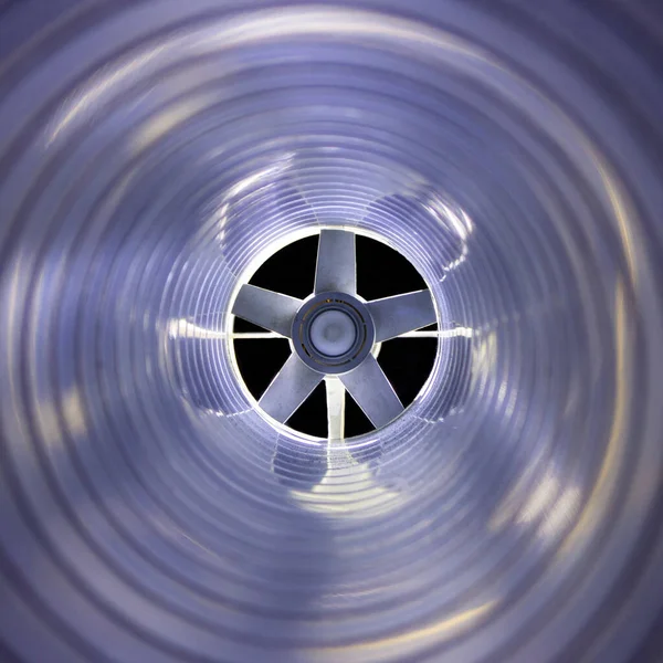 Arka plandaki egzoz vantilatöründeki galvanize çelik hava kanalının içerisinden yakın çekim görüntüsü Bokeh etkisi ile ön ve arka plan bulanıklaşır.