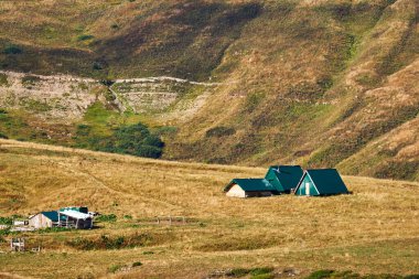 Kafkasya dağlarında sonbahar otlaklarının arka planındaki alp turist barınağı