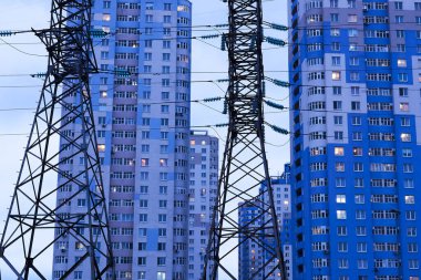 Elektrik hattı, akşam saatlerinde çok katlı apartmanların arka planına karşı destekliyor.