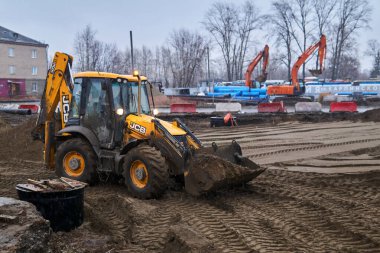 Perm, Rusya - 08 Kasım 2020: Yağmurlu havada bir sokak yolunun yeniden inşası sırasında kepçe doldurucu