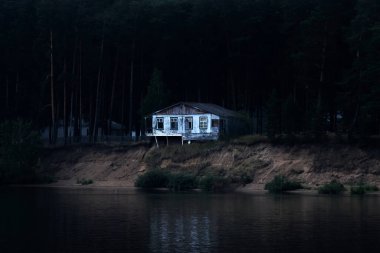 Terk edilmiş bir ev, karanlık bir ormanlık bir kıyıda nehre düşmek üzere.