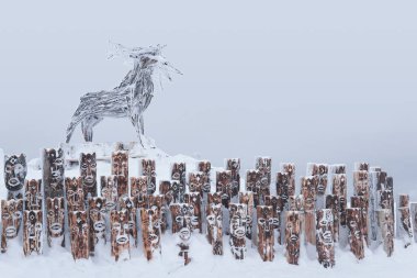 Perm Krai, Russia - January 02, 2021: snow-covered art object in the form of a group of idols depicting anthropomorphic figures and elk clipart