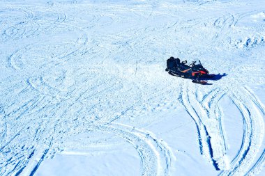 Karlı bir tarlada kar motorsikleti, birçok kar makinesi izi, üst görünüm