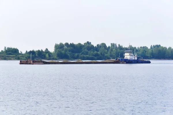 towboat pushes dry bulk cargo barge with sand on the river