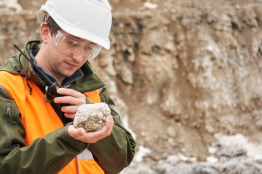 Erkek jeolog bir mineral örneğini inceliyor. 