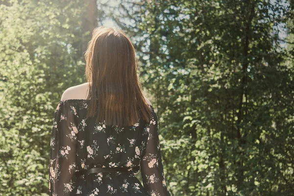 穿着衣服在阳光灿烂的自然公园里散步的年轻女子 — 图库照片